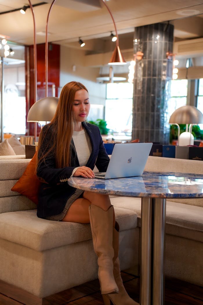 Woman in a stylish cafe working on her laptop, reflecting a professional lifestyle.