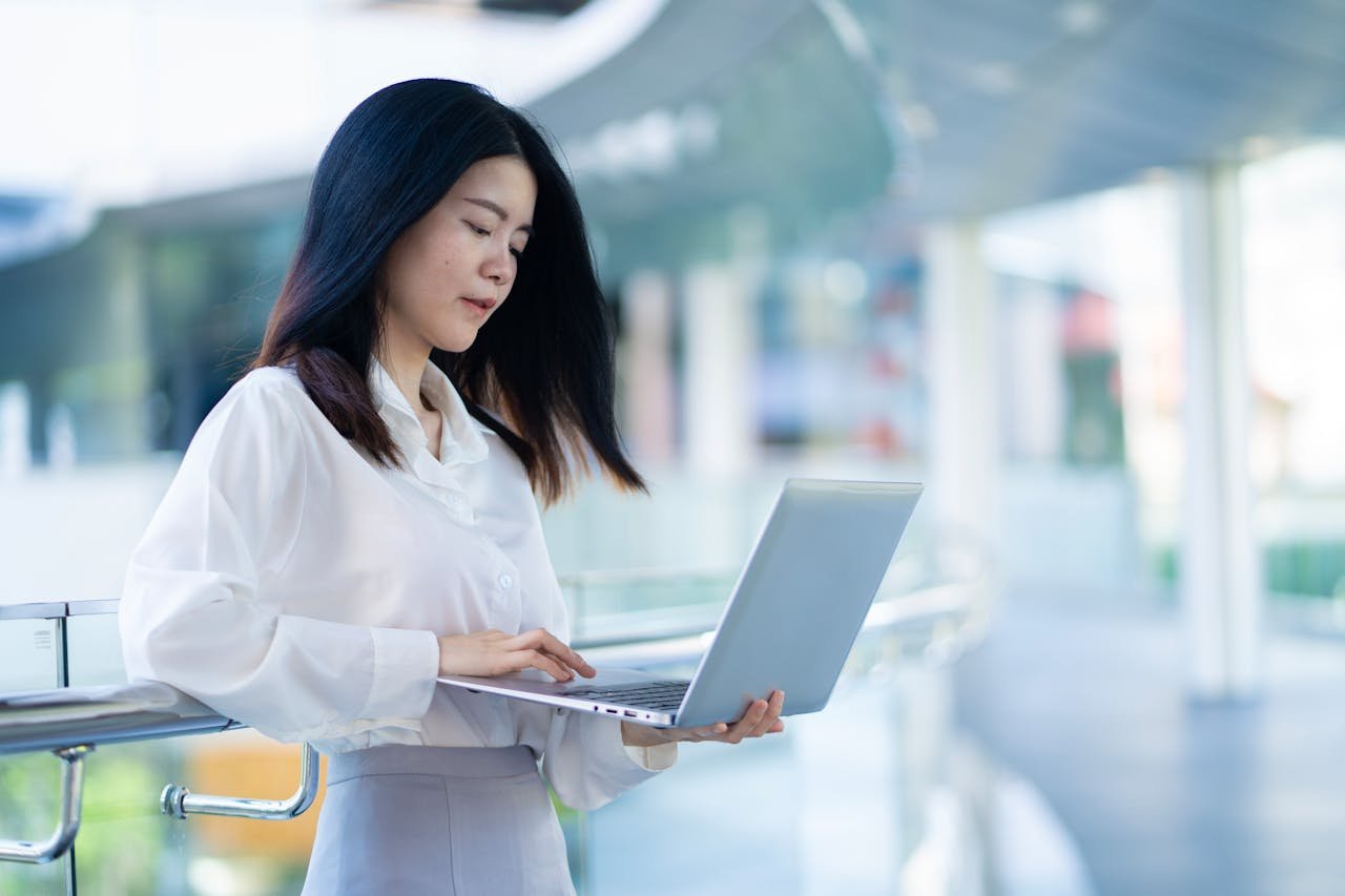 Asian businesswoman working remotely in a modern Bangkok office.